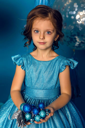 Girl in a blue dress holding a blue christmas balls