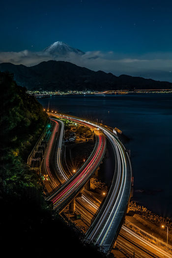 Aerial view of light trails on road against sky at night