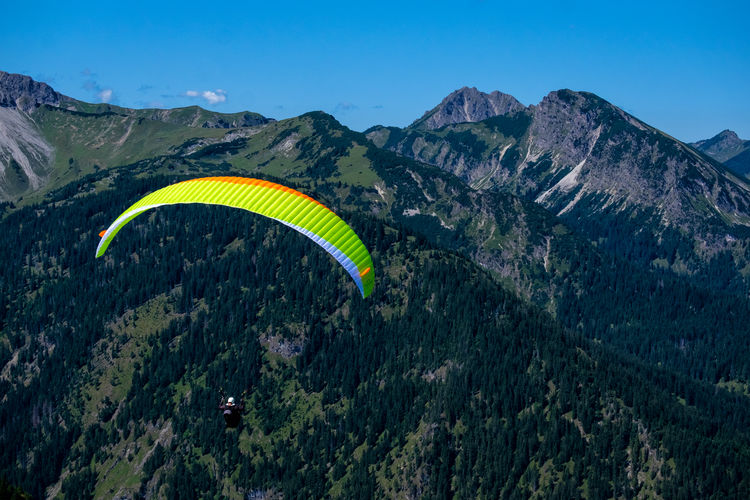 Scenic view of mountains against sky and paraglider