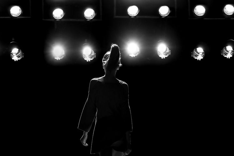Midsection of woman standing by illuminated lights at night