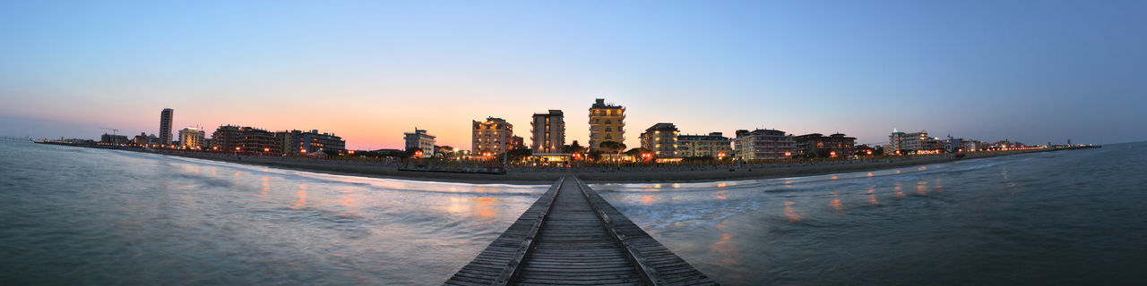 Beach promenade in italy, panoramic view of buildings against sky during sunset