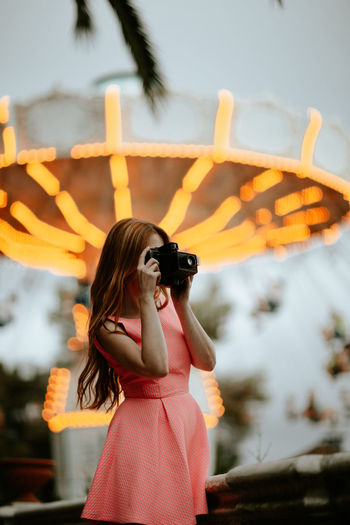 Millennial woman taking picture with camera in amusement park