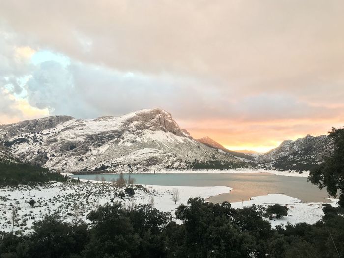 Scenic view of lake by mountains against sky during winter