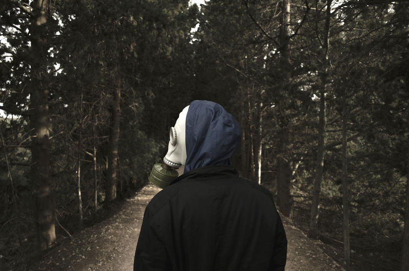 Rear view of man  with gas mask in forest