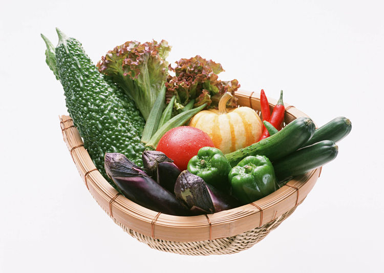 Fresh vegetables in basket against white background