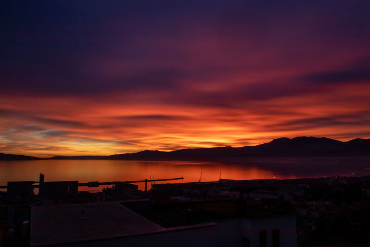 Scenic view of dramatic sky over town during sunset