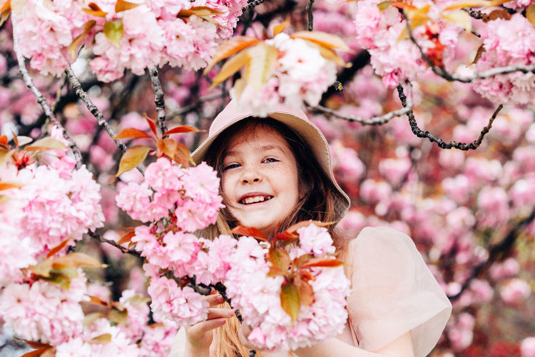 Portrait of cute girl standing by cherry tree