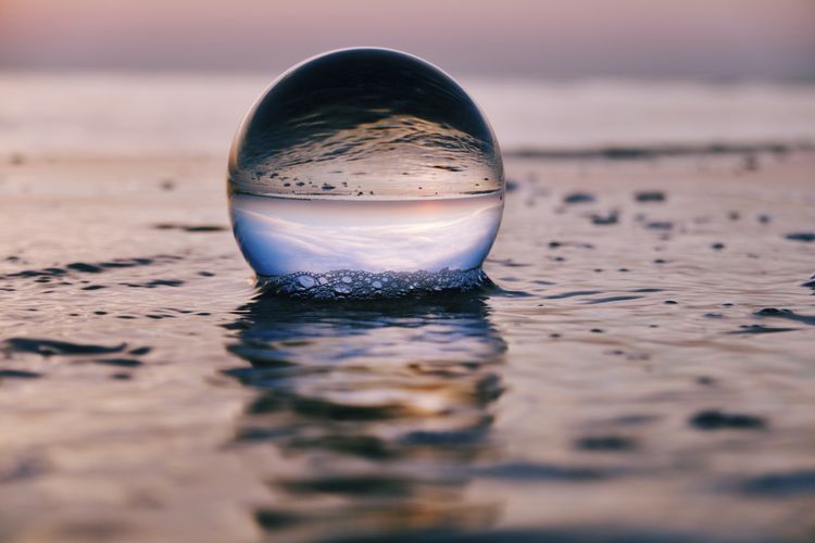 Close-up of crystal ball on beach during sunrise 