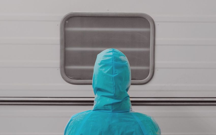 Rear view of person wearing raincoat against vehicle
