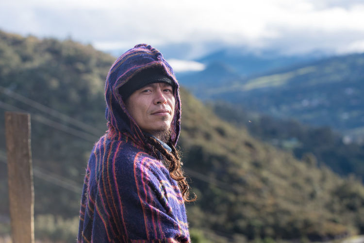 Portrait of colombian native american man in traditional clothing against mountains