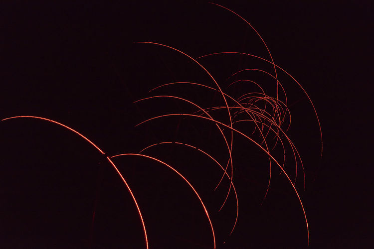 Low angle view of light trails against sky at night