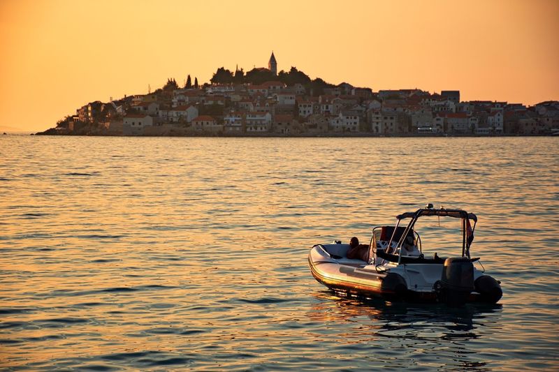 Scenic sunset on adriatic sea with cityscape of mediterranean town in background