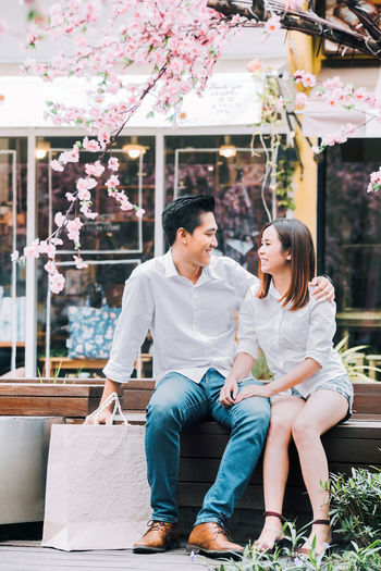 Smiling couple looking at each other while sitting on bench