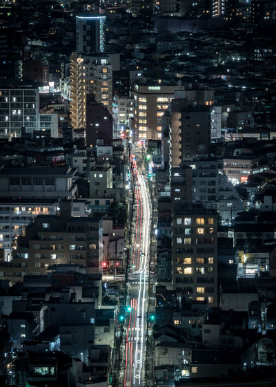 Aerial view of illuminated buildings and road in city at night