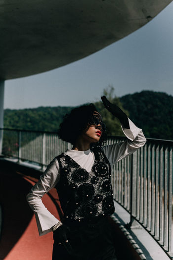 Woman standing by railing against sky