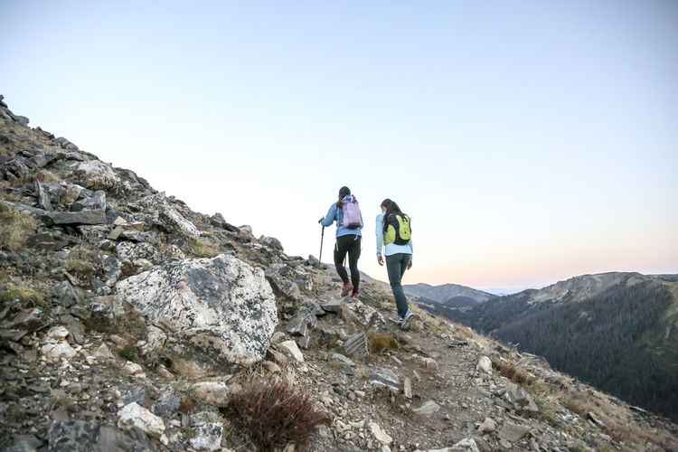 Two women trail runners push uphill in a rocky mountain early morning