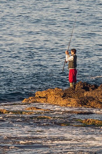 Full length of fisherman standing in water