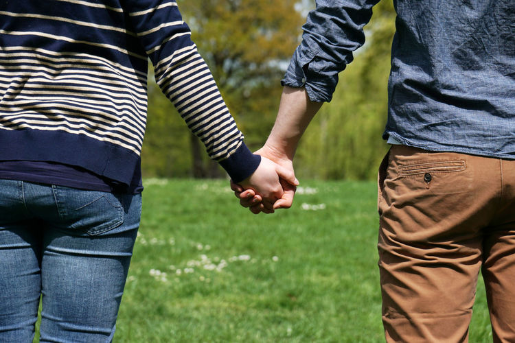 Midsection of couple holding hands at park