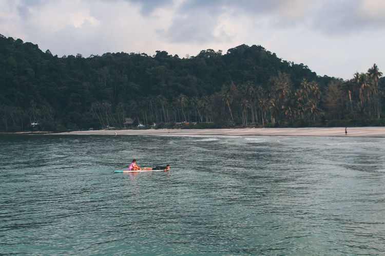 Man floating on sea against sky