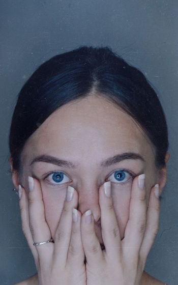 Close-up portrait of young woman against gray background