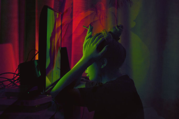 Side view of young woman working in illuminated room