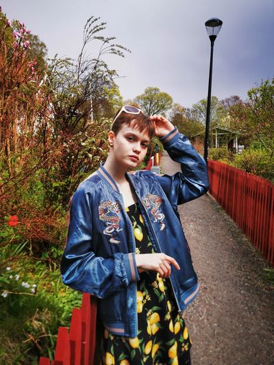 Young woman looking away while standing against plants