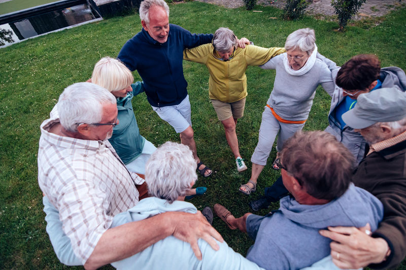 Group of happy seniors people dancing hugged together in circle oudoors