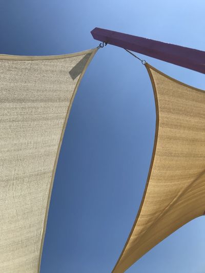 Low angle view of flags against clear blue sky