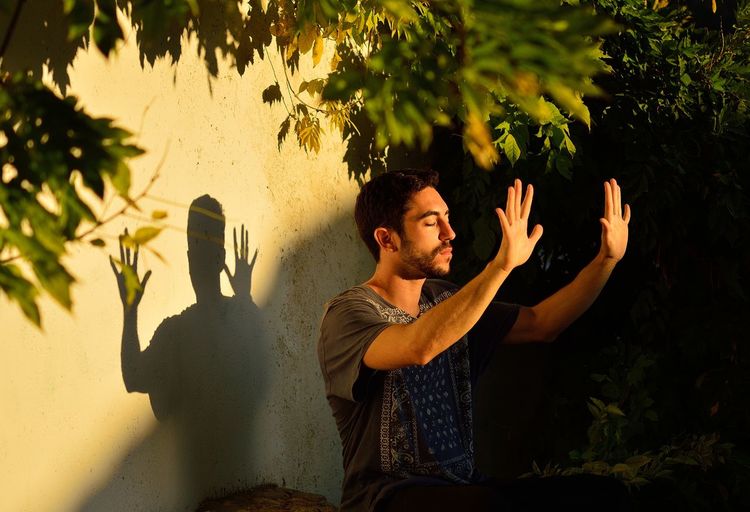 Young man gesturing while standing by wall