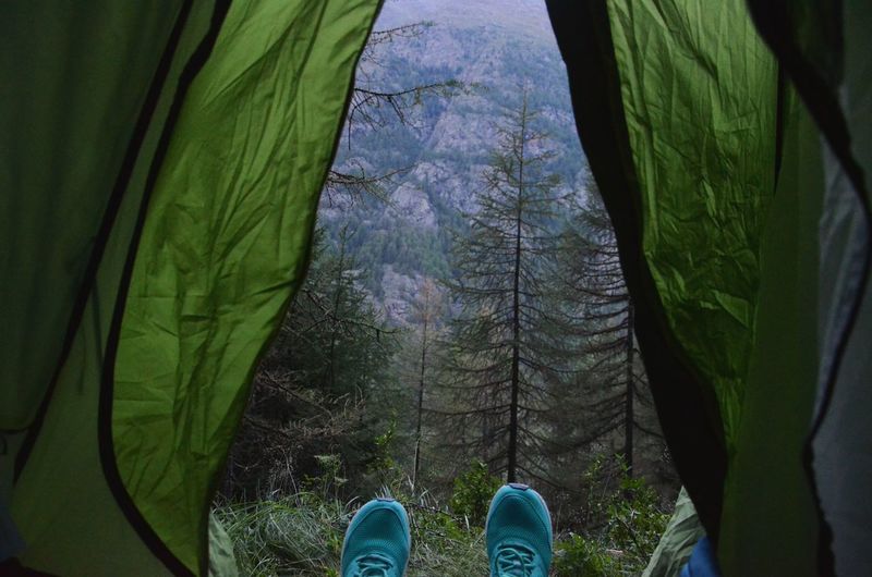 Low section of person relaxing in tent at forest