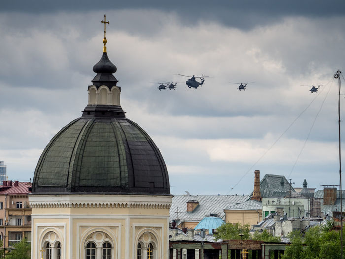 Military helicopters flying over buildings in city