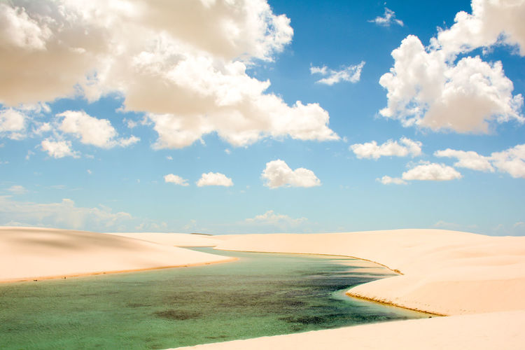 Scenic view of lagoon amidst sand dunes against sky