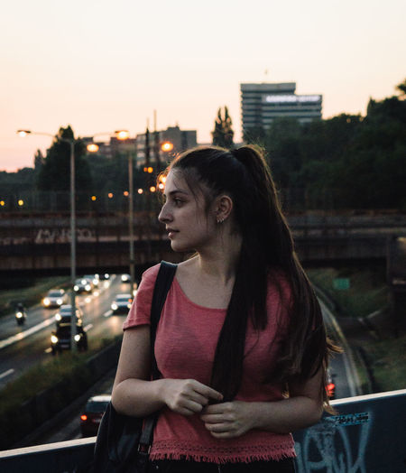 Young woman in city against sky