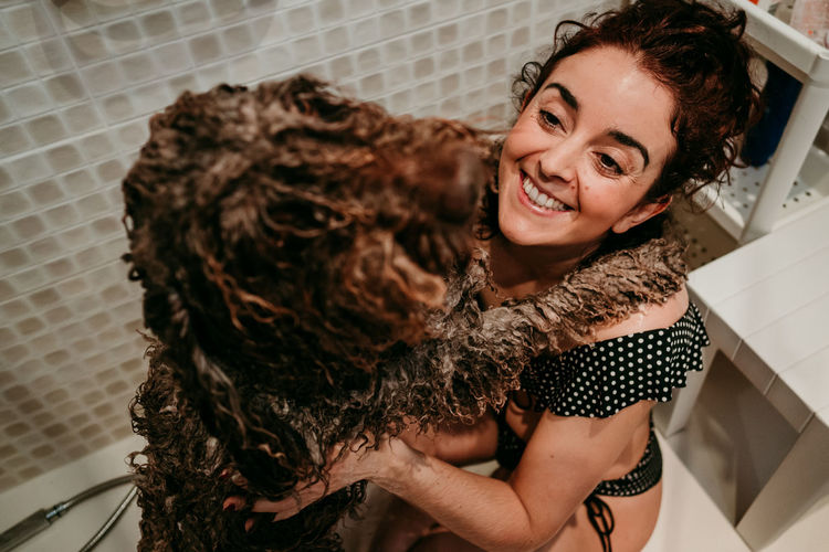 High angle view of smiling woman with dog in bathroom