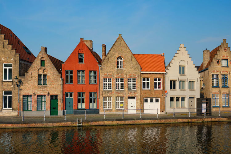 Houses by canal against sky in city