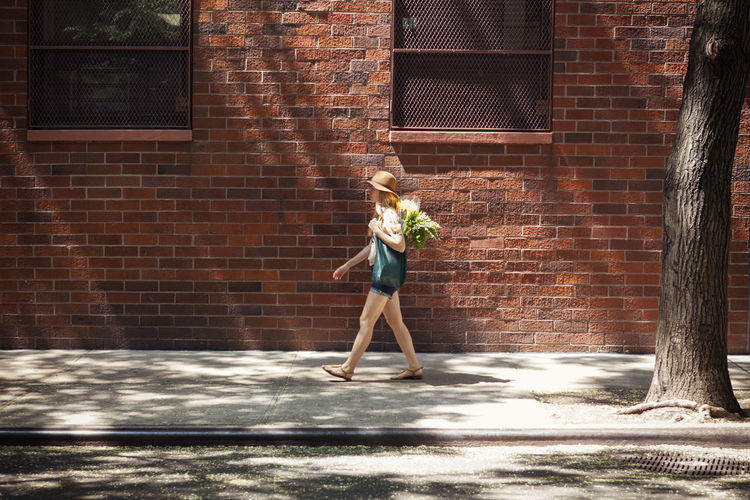 Full length of woman walking on sidewalk against building