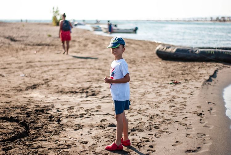 Boy in cap standing at beach