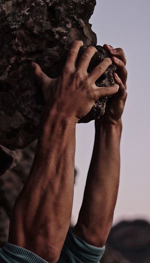 Close-up of man hanging from rock formation