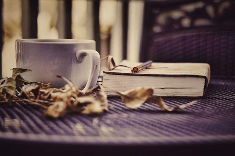 Coffee with dried leaves and book on table
