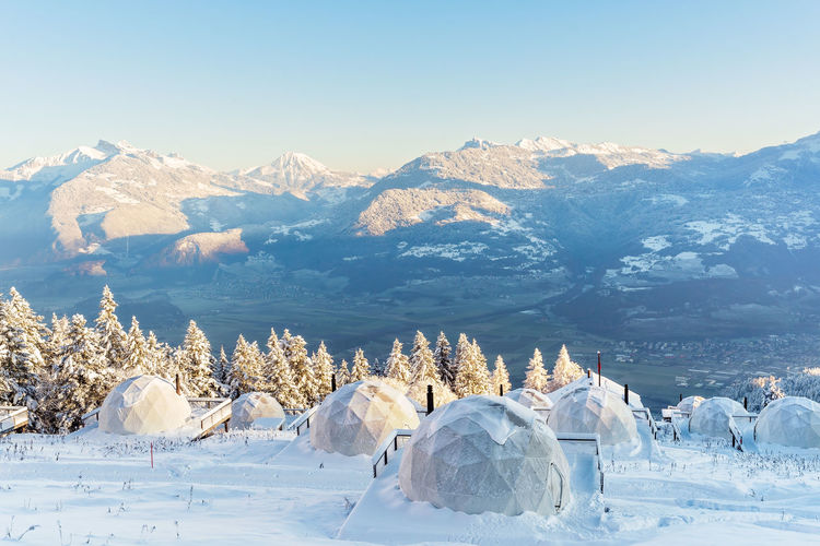 Winter igloo eco hotel in swiss mountauns covered by white snow at sunrise  with amazing view. 
