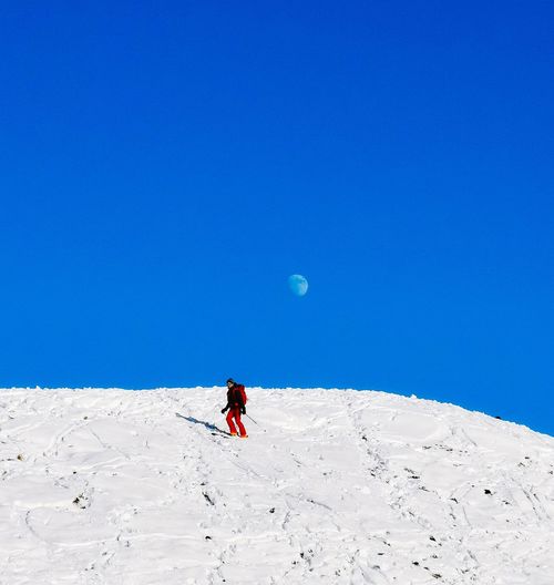 Full length of person on snowcapped mountain against clear blue sky