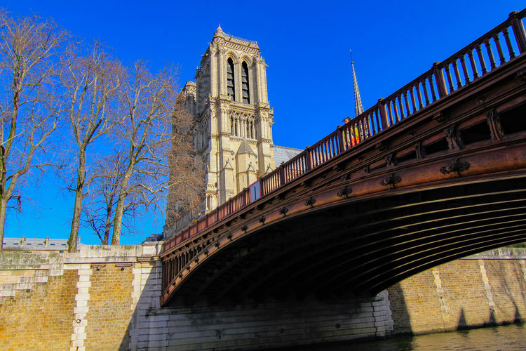 Low angle view of bridge and building against blue sky