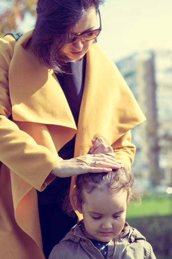Little girl's mother helping her with hair and making a ponytail.