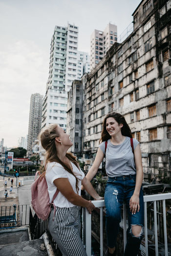 Smiling friends against buildings in city