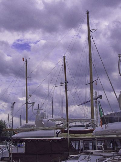 Boats in harbor against cloudy sky