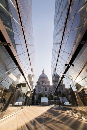 Perspective view of saint paul cathedral between shiny glass walls of futuristic skyscrapers in city of london