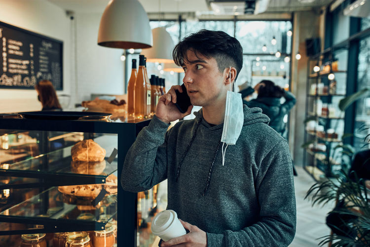 Man talking on phone at cafe, having important phone call, answering call, chatting by mobile phone
