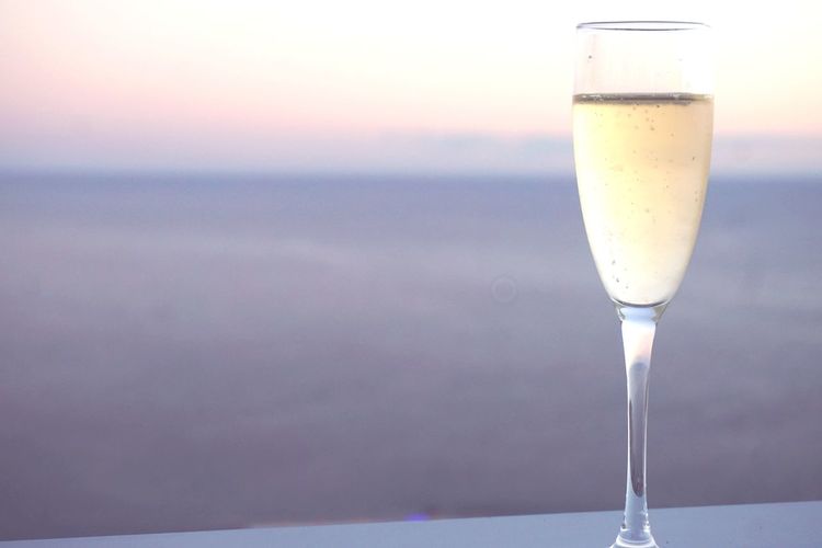 Close-up of champagne glass against sky during sunset