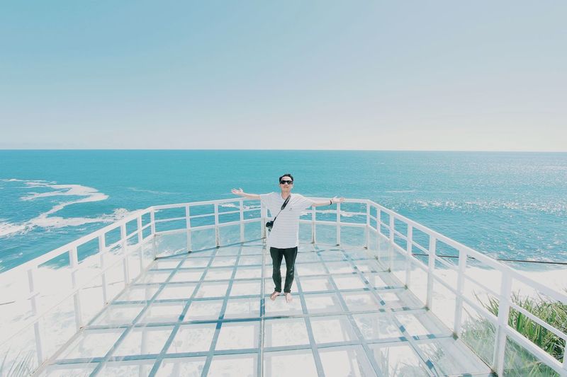 Full length of man standing by railing against sea