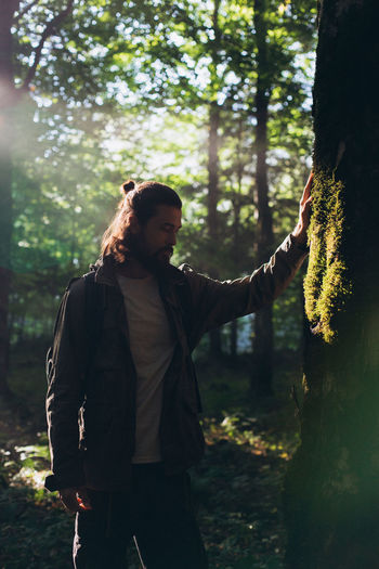 Man with beards standing by tree in forest